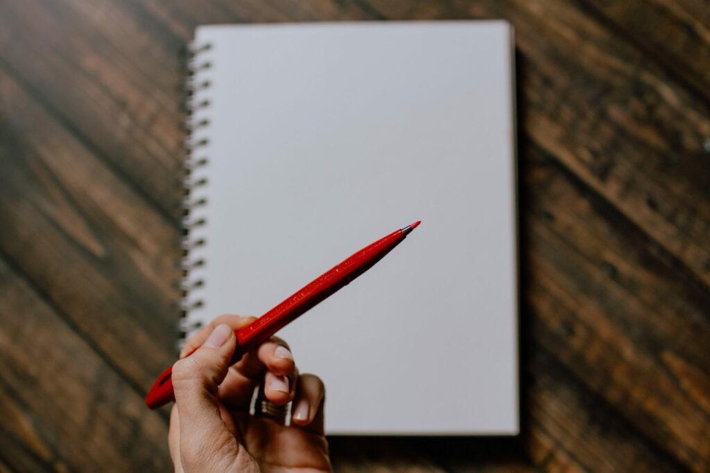 Blank notebook page with hand preparing to write on