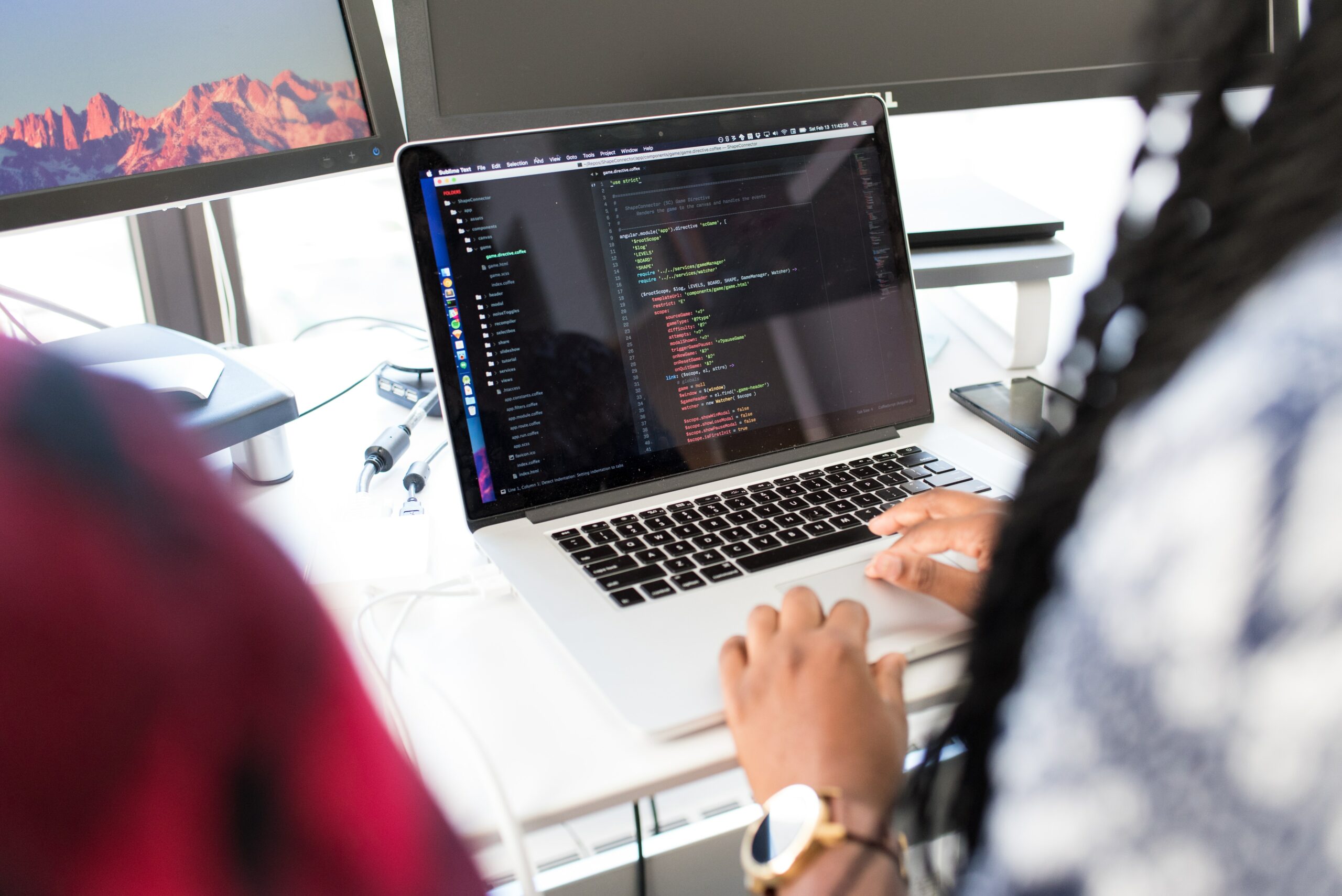 An image of a person writing code on a laptop.